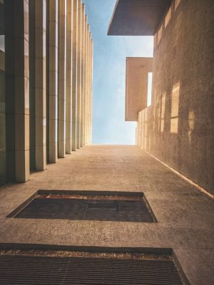 Looking up at a modern building's clean lines and geometric forms meeting the blue sky.