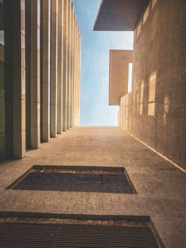 Looking up at a modern building's clean lines and geometric forms meeting the blue sky.